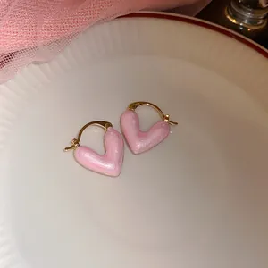 Gedetailleerd overzicht van zoete roze parelmoer hartvormige oorbellen met gouden ringen