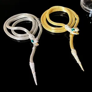 Close-up of gold and silver rhinestone snake tassel necklaces on black background
