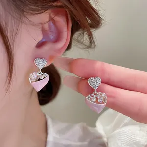 Close-up van elegante roze hart oorbellen met bloemdetails en kristallen hartjes