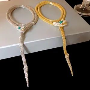 Close-up of gold and silver rhinestone snake fringe necklaces with emerald eyes