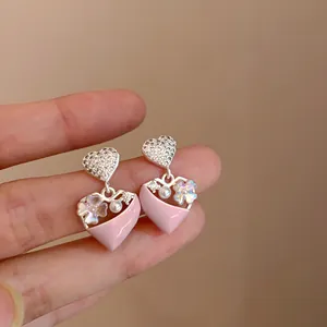 Detailweergave van roze hartoorbellen met delicate bloemen en fonkelende strass