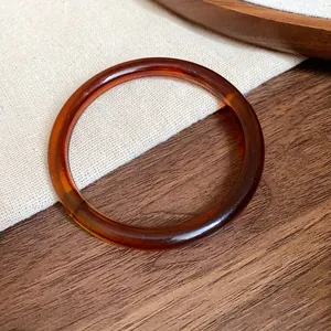 Detailed macro view of a vintage amber acetate bangle resting on a wooden surface