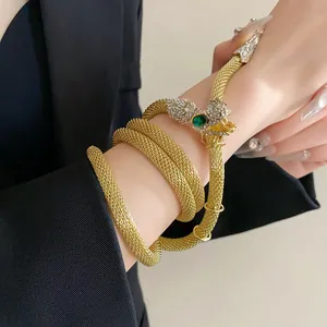 Exquisite detail of a luxury gold snake necklace with green eyes wrapped as a bracelet