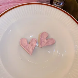 Close-up van roze hartvormige oorbellen met textuur op een wit keramisch bord