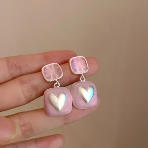 Detailopname van roze vierkante hangers met een zilveren hart in een zoete stijl.
