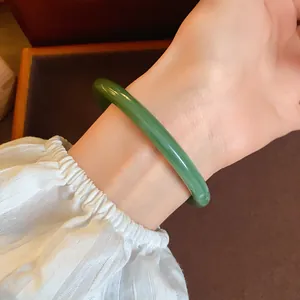 Close-up of a vintage-style green acrylic acetate bangle worn on a woman's wrist