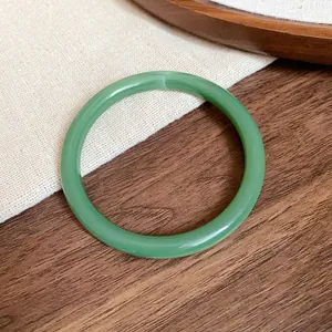 Detail of a translucent green acrylic acetate bangle on a textured background