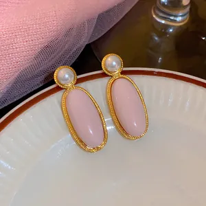 Vintage goudkleurige ovale oorbellen met gladde roze stenen en verfijnde witte parels.