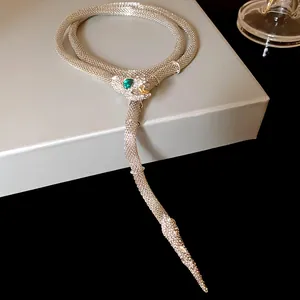 Detailed macro view of heavy rhinestone snake tassel necklace featuring green stones