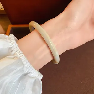 Close-up of a vintage cream-colored acetate bangle bracelet worn on a wrist