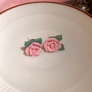 Gedetailleerde close-up van roze roos oorknopjes met groene bladeren op een vintage bord