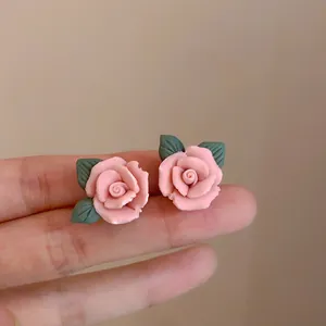 Close-up van handgemaakte roze roos oorknopjes met groene bladeren