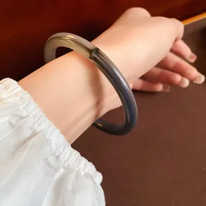 Detail shot of a retro grey two-tone acetate bangle worn on a wrist