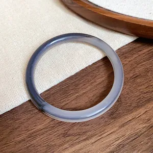 Macro view of a translucent grey acetate bracelet on a textured wooden background