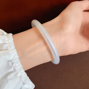 Close-up of a translucent white acrylic bangle worn on a wrist with a ruffled sleeve