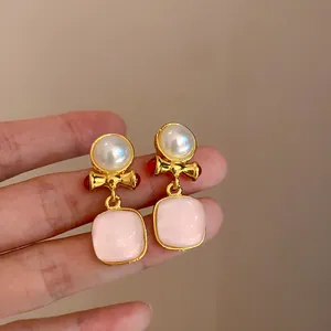 Gedetailleerd macrobeeld van vintage gouden oorbellen met roze vierkante stenen en parels