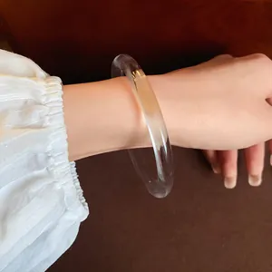 Detail shot of a minimalist clear acrylic bangle showing smooth texture and transparency.