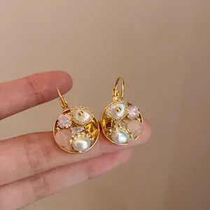 Close-up van goudkleurige oorbellen met parels, kristallen en delicate roze edelstenen