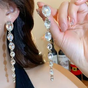 Detail von langen Strass-Hängeohrringen mit Gold-Finish und klaren facettierten Steinen