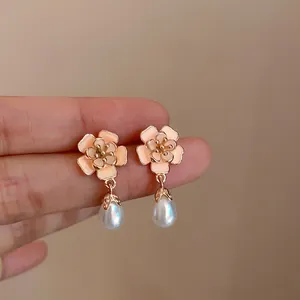 Detailopname van roze emaille bloemoorbellen met elegante pareldruppels en een gouden afwerking