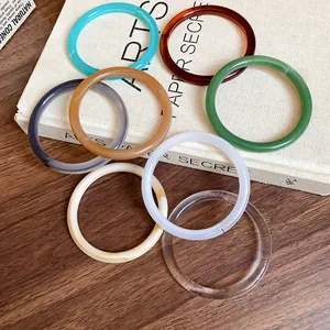 Collection of colorful vintage acrylic acetate wide bangles on a textured book cover