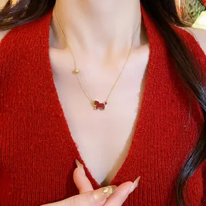 Dainty gold chain necklace featuring a red horse pendant worn by a female model.