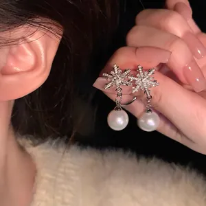 Detailed view of silver snowflake earrings with sparkling crystals and drop pearls