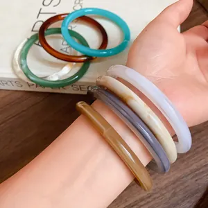 Close-up detail of colorful vintage acrylic acetate bangles worn on a model's wrist