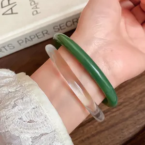 Close-up detail of smooth green and clear acetate acrylic bangles worn on the wrist
