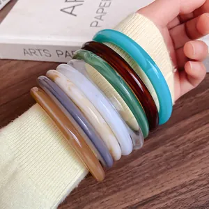 Detailed close-up of colorful retro acrylic acetate bangles stacked on a woman's wrist