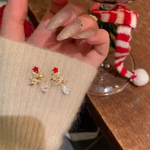 Close-up of Christmas tree drop earrings with sparkling crystals on knit fabric.