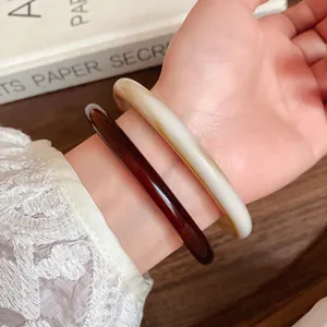 Detailed close-up of retro acrylic acetate bangles in coffee and cream on wrist