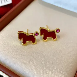 Detailed close-up view of gold-plated pony earrings with red enamel and pink zircon stones