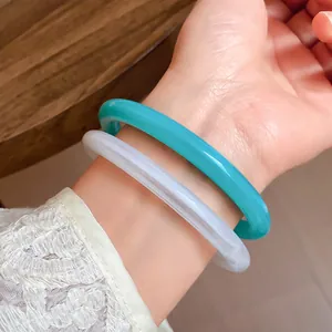 Detailed macro view of teal and translucent white vintage acrylic acetate bangles worn on wrist