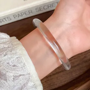 Close-up detail of a clear transparent acrylic bangle bracelet on a female wrist