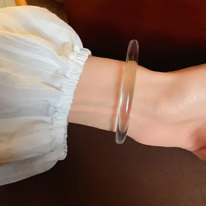Close-up of a clear transparent acrylic geometric bracelet on a wrist with a pleated sleeve