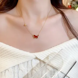 Detailed view of an elegant gold necklace featuring a red horse pendant on a neck