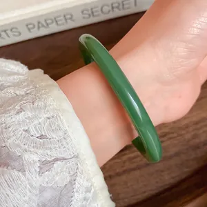 Detail of a minimalist green acrylic bangle on a wrist featuring white lace detail