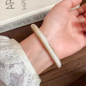 Detailed macro view of a retro geometric off-white acetate bangle worn on a wrist