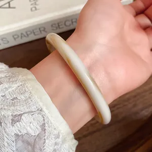 Close-up of vintage marbled acetate wide bangle on wrist for niche summer style