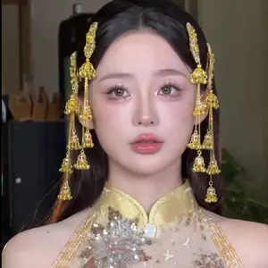 Détail de barrettes de style ethnique avec glands de cloche dorés et fleurs en strass.