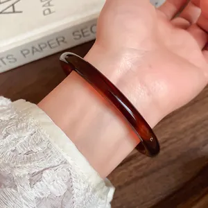 Close-up macro view of a vintage amber acrylic bangle bracelet on a woman's wrist