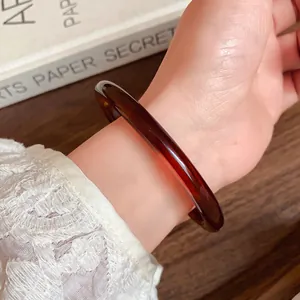 Close-up of retro brown translucent acetate bracelet worn on a stylish female wrist