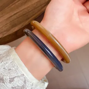Close-up view showing retro acrylic acetate bangle bracelets in amber and navy blue colors