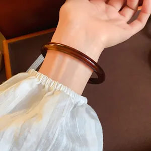 Detailed view of a vintage amber acrylic acetate bangle worn on a woman's wrist