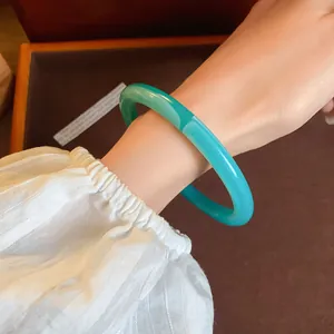 Close-up of a stylish green translucent acrylic acetate bangle worn on a feminine wrist