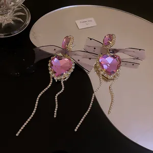 Macro view of purple heart earrings with rhinestones and elegant mesh ribbon tassels.
