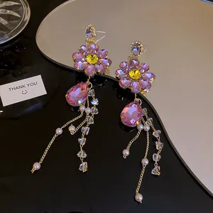 Close-up detail of elegant purple flower crystal dangle earrings with long gold tassel and pearls