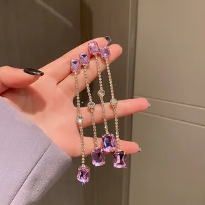 Detailed macro shot showing elegant long tassel earrings with purple rectangular gems.