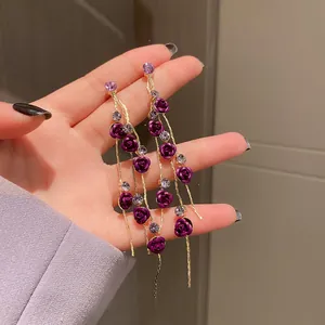 Detailed view of long purple flower tassel earrings with crystal accents and gold chain.